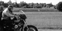 A motorcyclist bows into the headwind as he accelerates on the interstate.